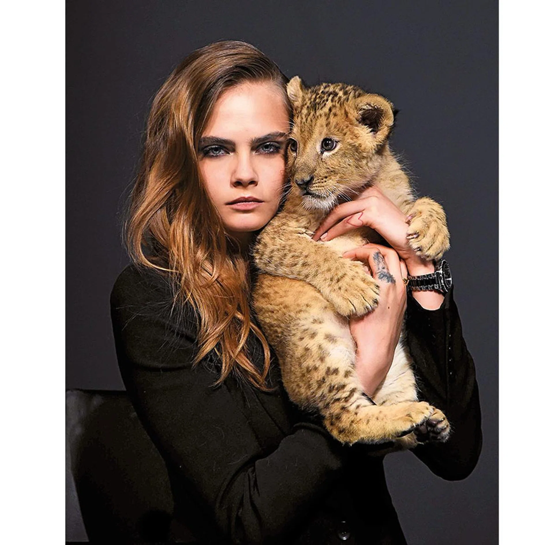 Born under the sign of Leo herself, Delevinge cuddles a lion cub at TAG Heuer photocall.
