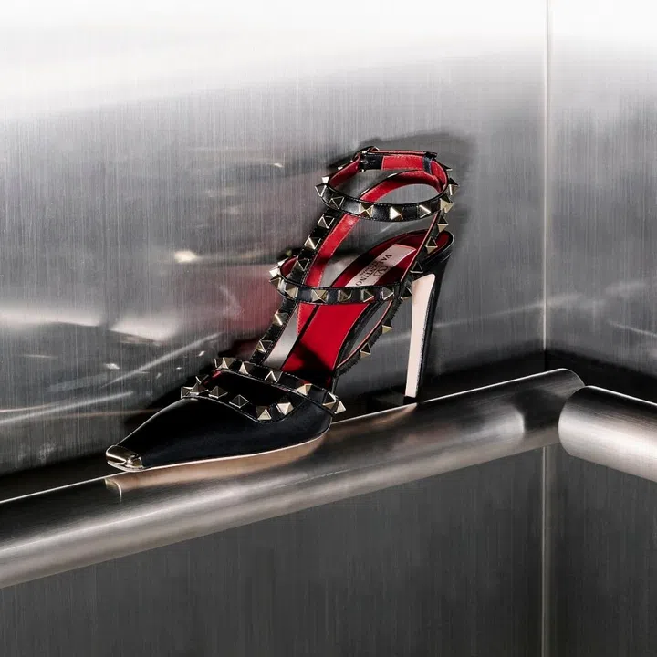 Side profile of the 2026 Valentino Rockstud pump in black leather with signature gold pyramid studs and red interior lining