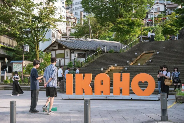 IKAHO sign and tourists at the beginning of the Stone Steps Street in Shibukawa Ikaho Onsen Town.