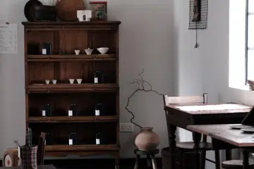Aesthetic interior of Inner Teahouse in Chinatown Singapore featuring dark wood vintage furniture, rare Fujian tea tins on shelves, and a minimalist Kyoto-inspired salon atmosphere