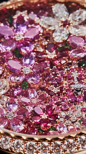 A watch from Dior mimicking a lush garden, featuring a rose gold dial set with diamonds, pink sapphires, rubies and tsavorite garnets.