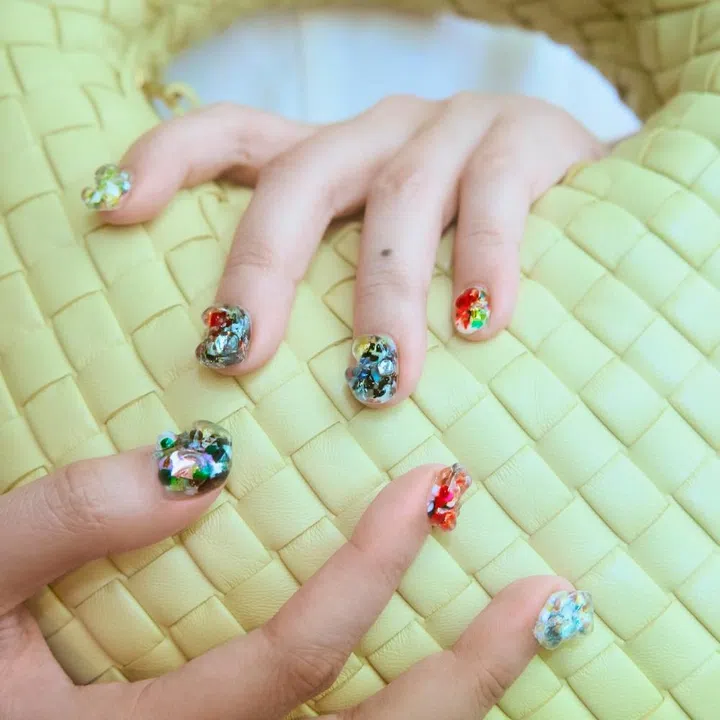 Sculptural gel nail art by Part Time Nails on Bottega Veneta yellow Intrecciato leather Baby Veneta bag.