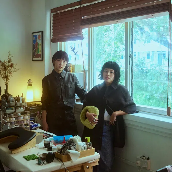 Part Time Nails co-founders Yi Lu and Edna Sun in their studio for F ZINE, wearing Bottega Veneta leather ready-to-wear and holding the yellow Intrecciato Baby Veneta bag.