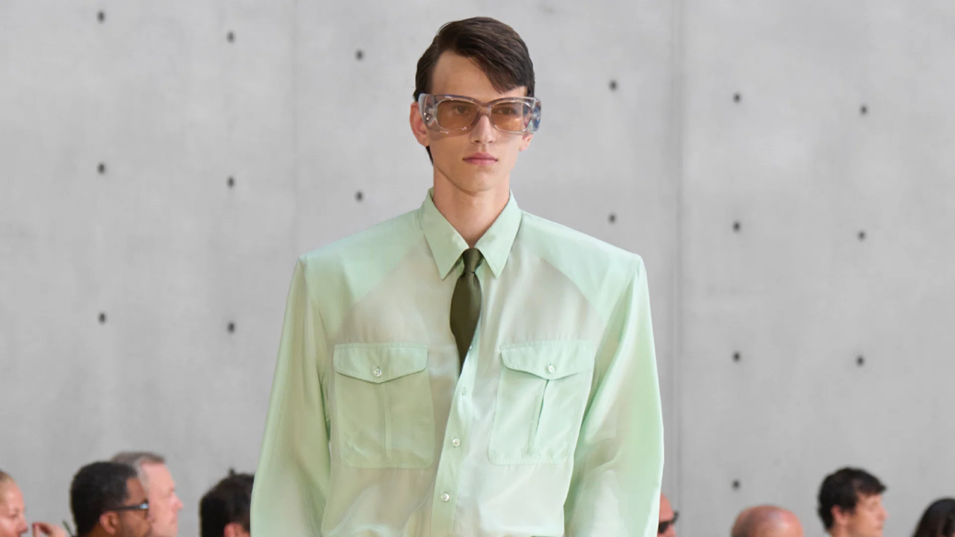 A model walking down the runway with a tucked in tie.