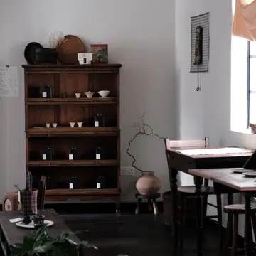 Aesthetic interior of Inner Teahouse in Chinatown Singapore featuring dark wood vintage furniture, rare Fujian tea tins on shelves, and a minimalist Kyoto-inspired salon atmosphere