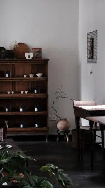 Aesthetic interior of Inner Teahouse in Chinatown Singapore featuring dark wood vintage furniture, rare Fujian tea tins on shelves, and a minimalist Kyoto-inspired salon atmosphere