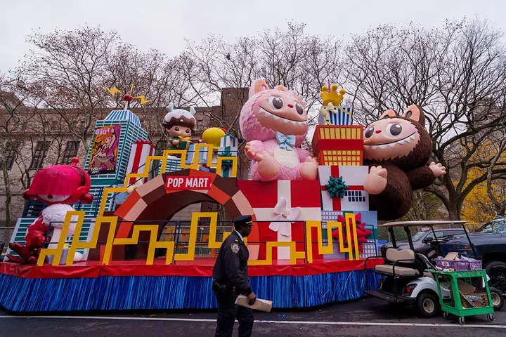 NEW YORK, NEW YORK - NOVEMBER 26: An NYPD officer walks past Labubu and the Friends-giving in POP CITY theme float during Macy's Balloon Inflation 2025 on November 26, 2025 in New York City. This year will be the 99th annual marching of the Macy's Thanksgiving Day Parade, and will feature a new Mario and Buzz Lightyear balloons and a LABUBU float, among others. (Photo by Adam Gray/Getty Images)