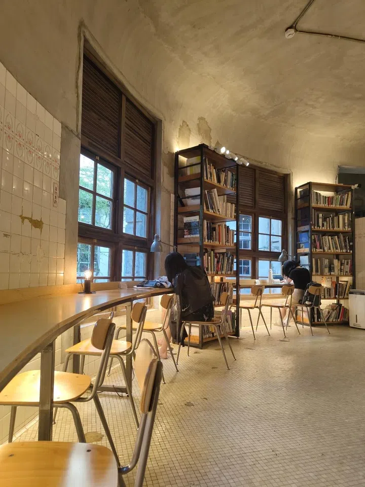  The interior of Not Just Library in Taipei, a minimalist design library housed in a converted historic bathhouse with vaulted ceilings and original tiled walls.