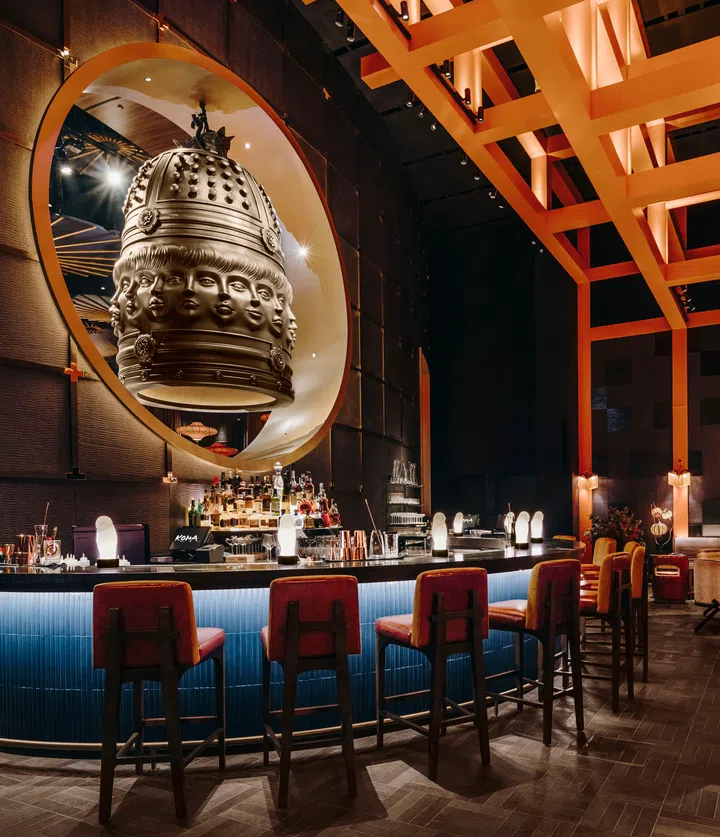 Japanese bell hanging above the bar at Koma Marina Bay Sands, surrounded by warm lighting and torii-inspired wooden grid ceiling