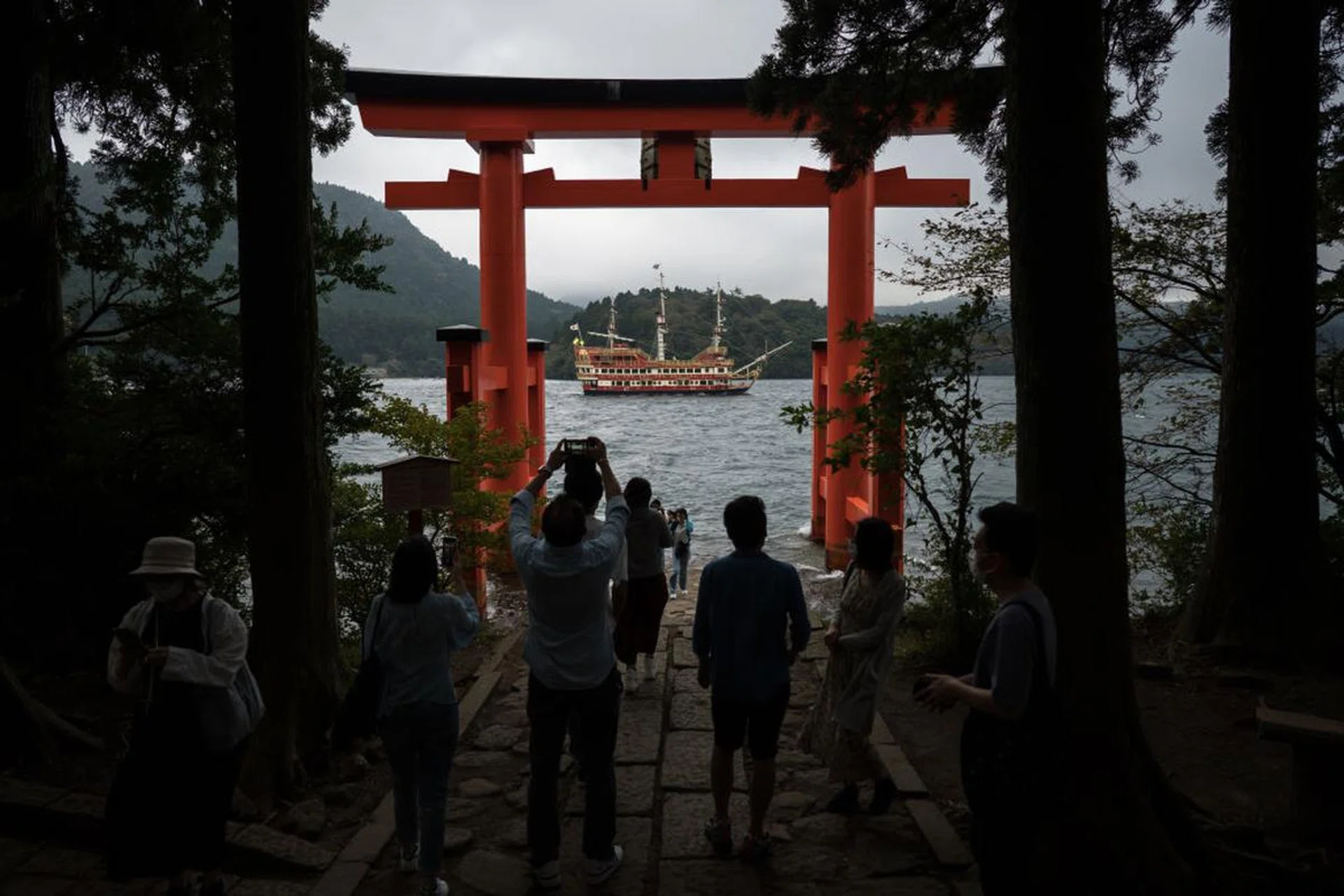 HAKONE, JAPAN - OCTOBER 04: Tourists take photographs of a pirate ship cruise sailing on Ashinoko Lake through the Torii of Peace at Hakone Shrine on October 04, 2022 in Hakone, Japan. Japan's Prime Minister Fumio Kishida unveiled a multi-billion dollar package for the nation's tourism industry as the country plans to open its border to individual tourists on October 11. A weaker yen is expected to help more foreign tourists visiting the country. (Photo by Tomohiro Ohsumi/Getty Images)