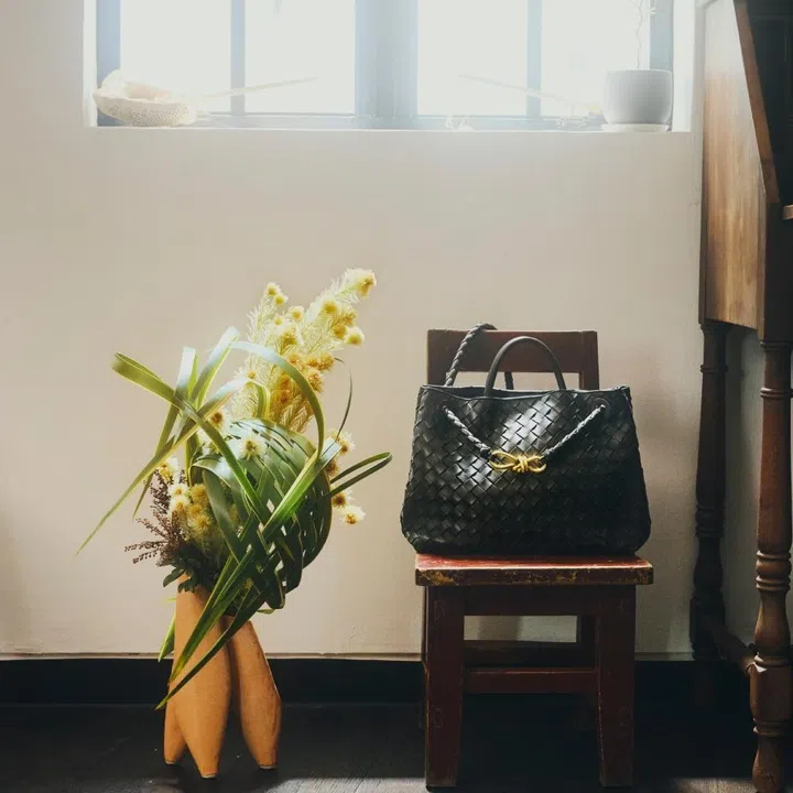 Bottega Veneta black Andiamo bag and Zoe Chen’s woven botanical arrangement in a sunlit studio for F ZINE.