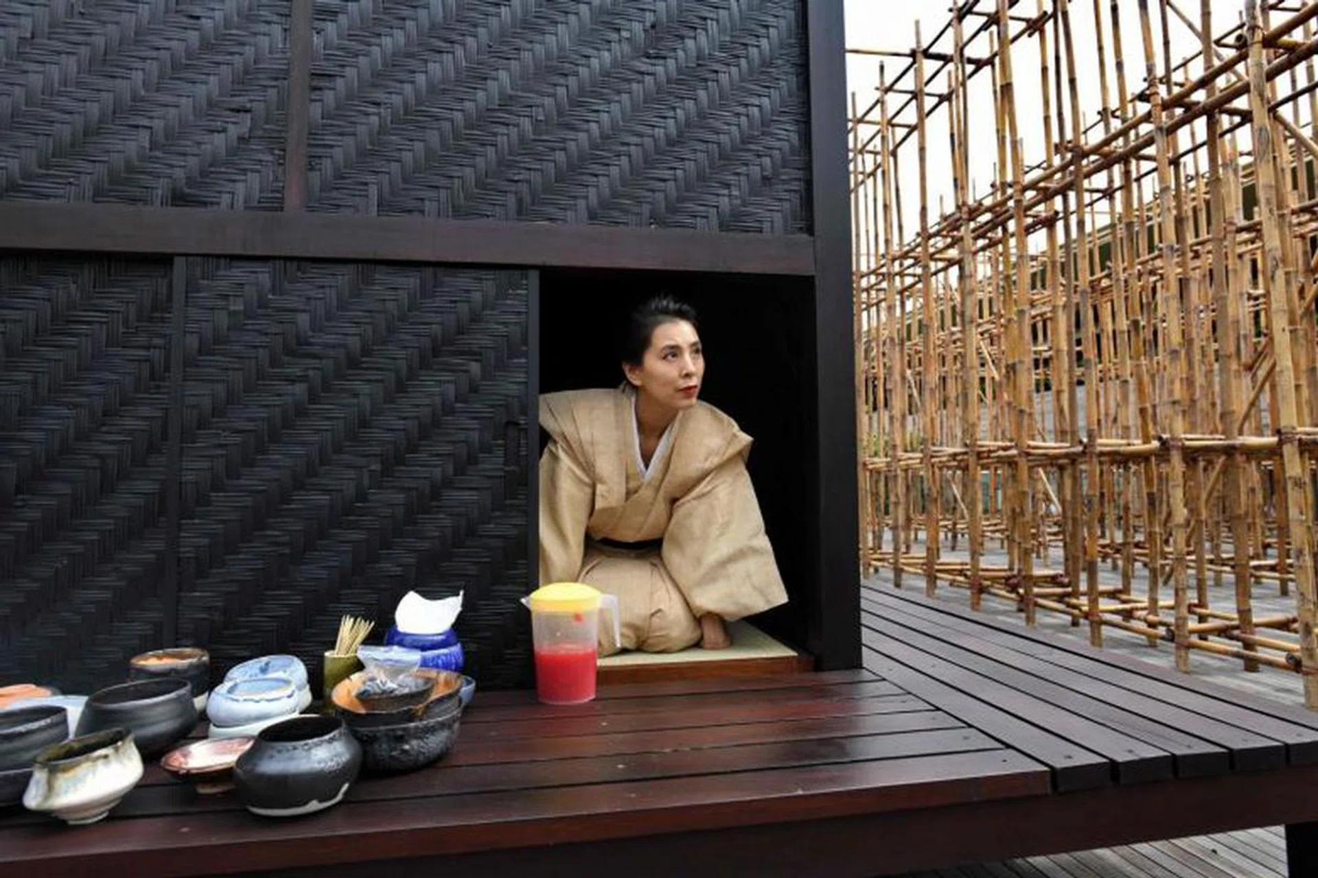 Japanese tea ceremony performance artist Mai Ueda looking out from a wooden tea house, part of a bamboo maze installation display by artist Rirkrit Tiravanija, on the roof of the National Gallery Singapore. Photo: AFP