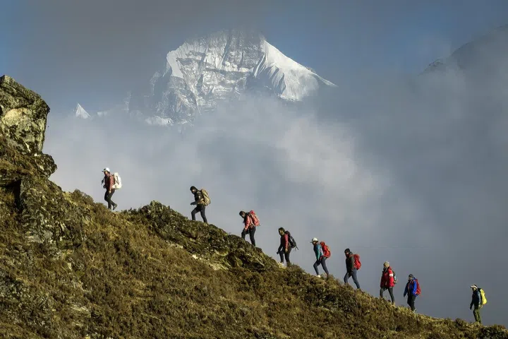 Dawa Yangzum Sherpa (left) is leading her group of young women towards the top of a ridge, with the white peaks offering an inspiring backdrop for these aspiring mountaineers.