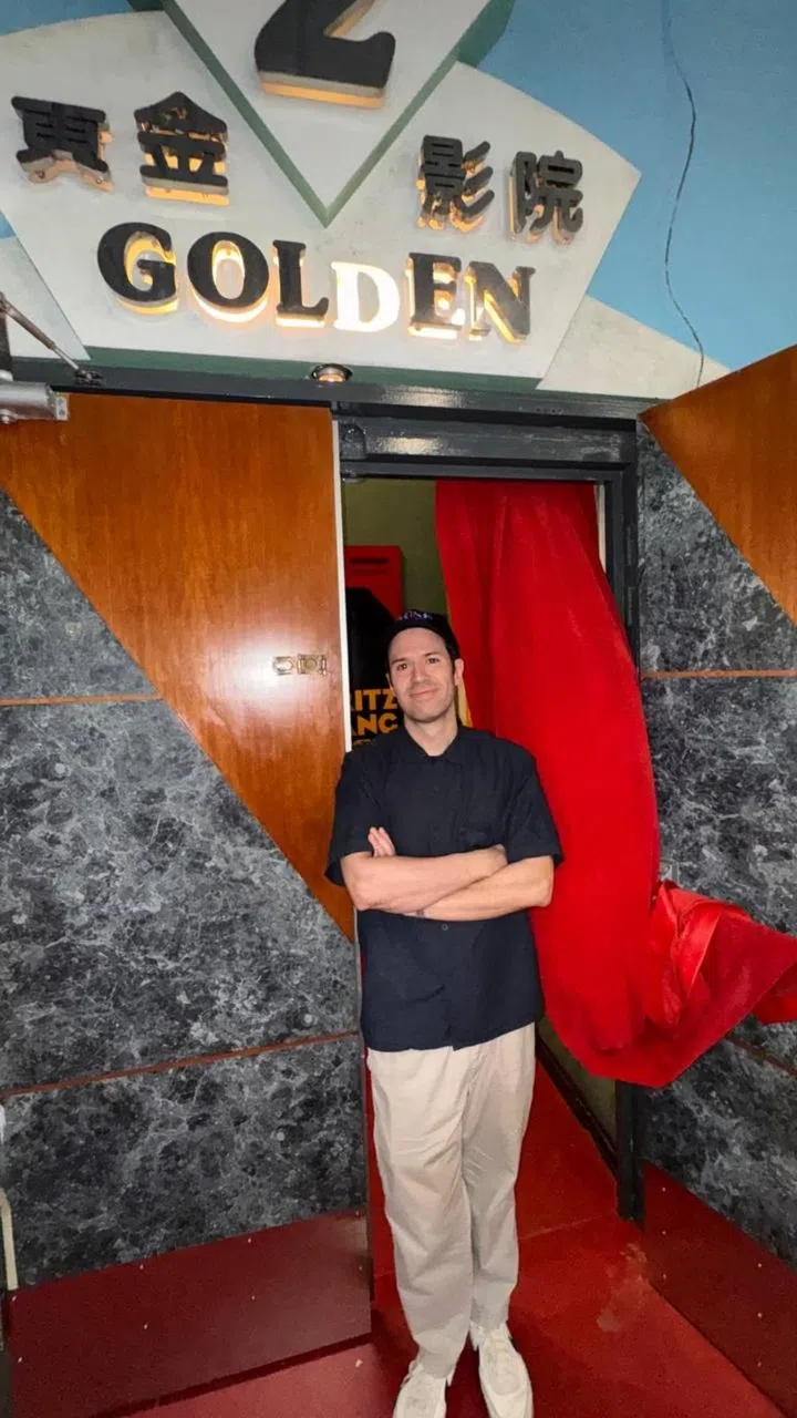 Walter Navarro, Filmhouse programmer, standing at the cinema entrance in Golden Mile Tower next to a red velvet curtain
