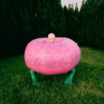 A surreal fashion photograph by Malaysian photographer Weeyang featuring a model in a large pink inflatable ring against a backdrop of pine trees.