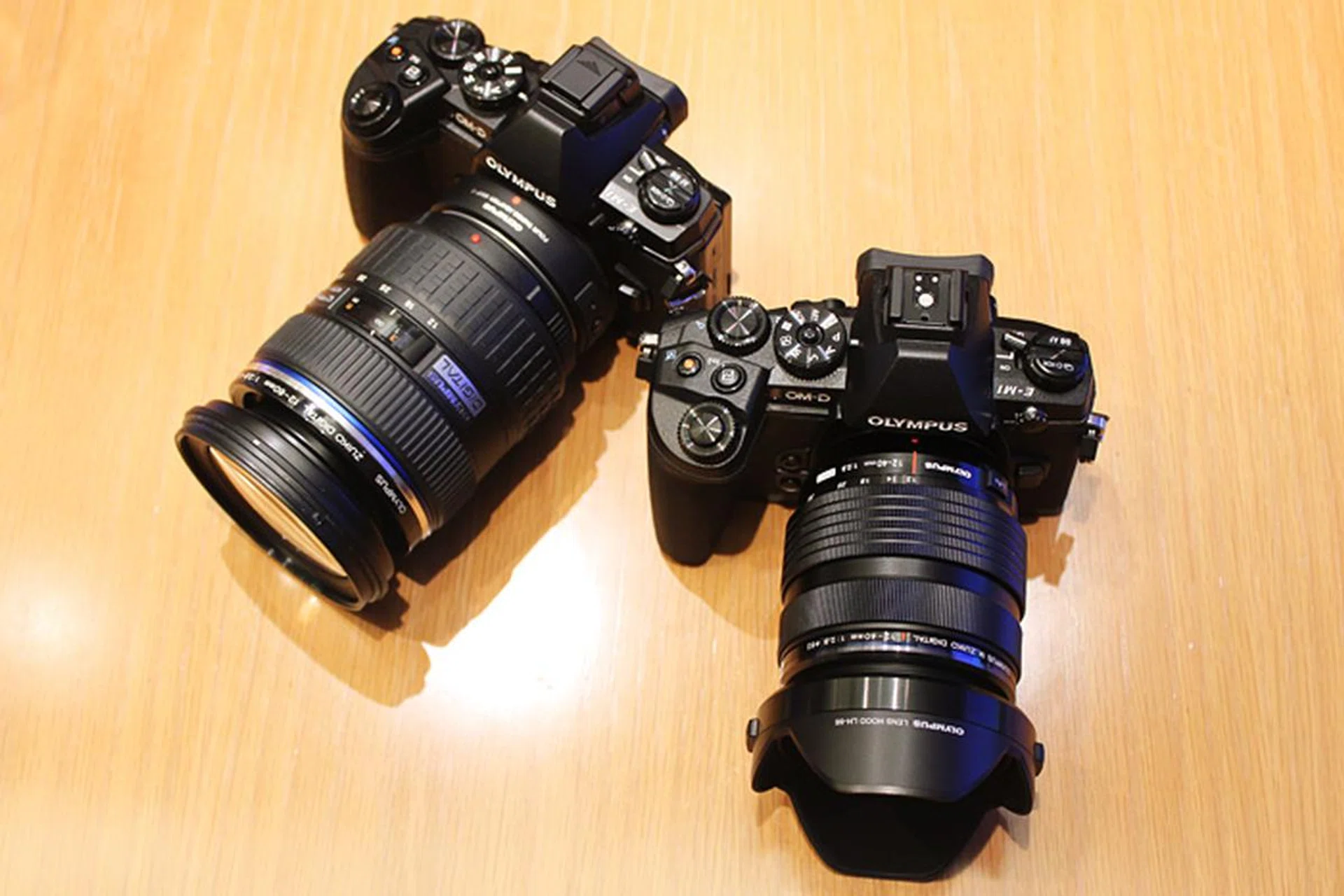 The E-M1 with a Four Thirds adapter and a Zuiko Digital lens (left), and an E-M1 with the new 12-40mm f/2.8 M.Zuiko Pro lens for Micro Four Thirds (right).