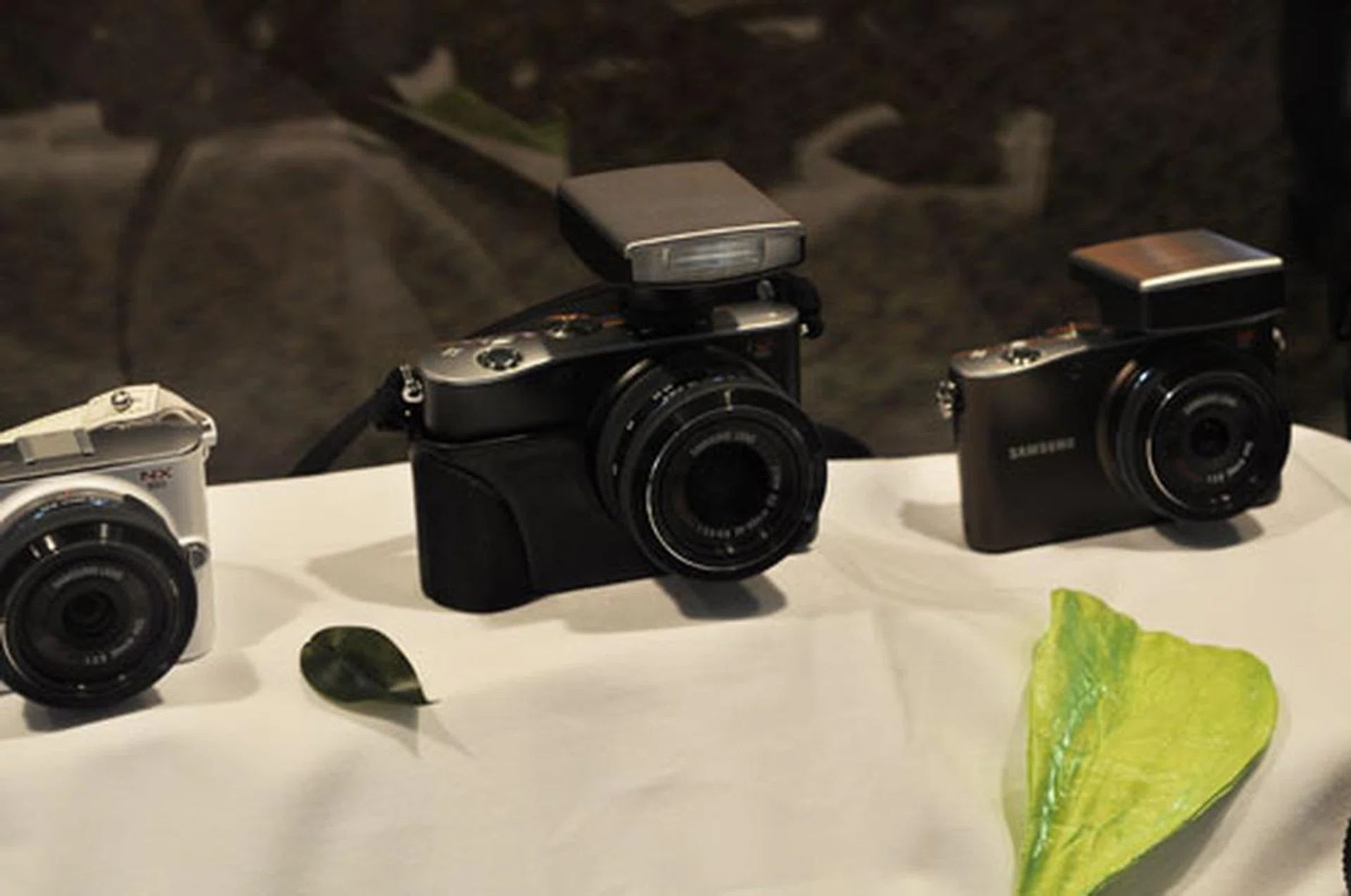 Shown here are NX100 cameras with the flash (center) and GPS attachments (right).