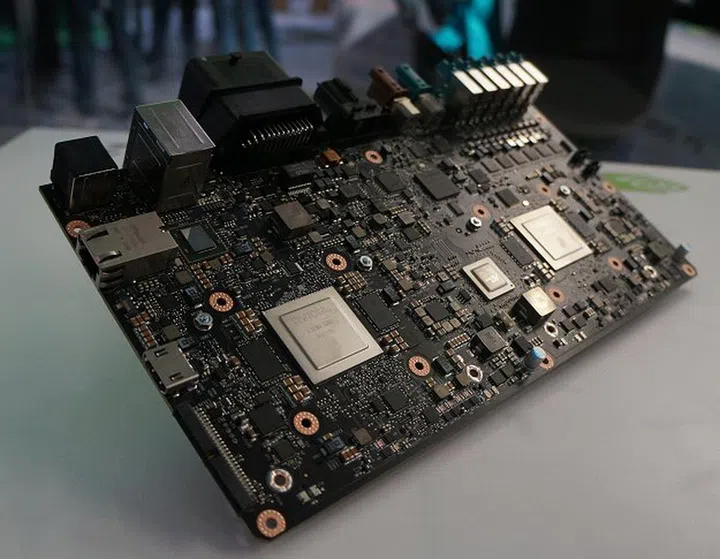 This is the elusive NVIDIA Drive PX 2 behind a glass box. What you're seeing is the front face that reveals the two next-gen Tegra processors and very likely a PLX PCIe switching chip to interface with the twin Pascal GPUs at the rear and their NVLink fabric.