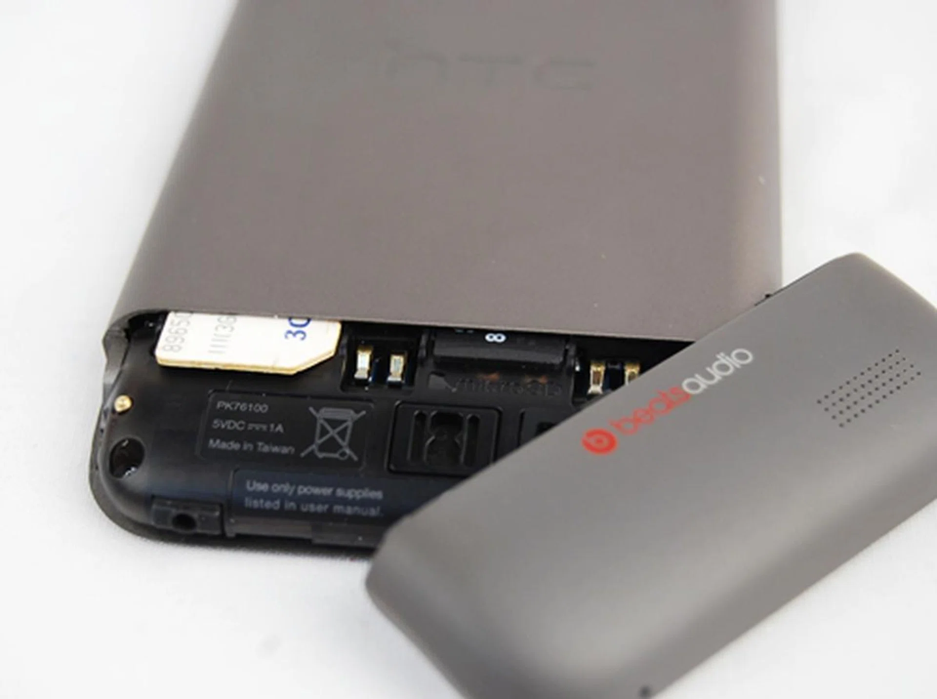 The battery is non-removable on the HTC One V so basically what you have to do is remove the small cover at the bottom (simply apply some pressure and it will slide off easily) and you will gain access to both the microSD and SIM card slots.