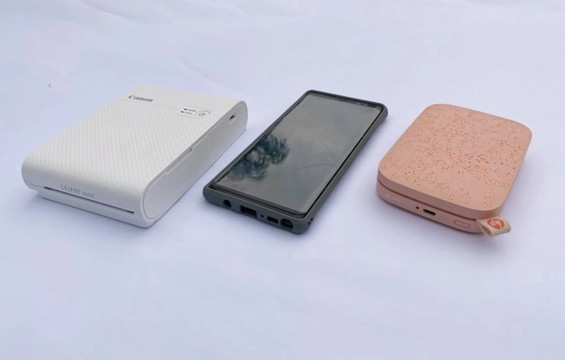 You can see the size differences between the Canon Selphy Square QX10, the HP SProcket 2 and the Samsung Galaxy Note 8 smartphone for an added point of reference.