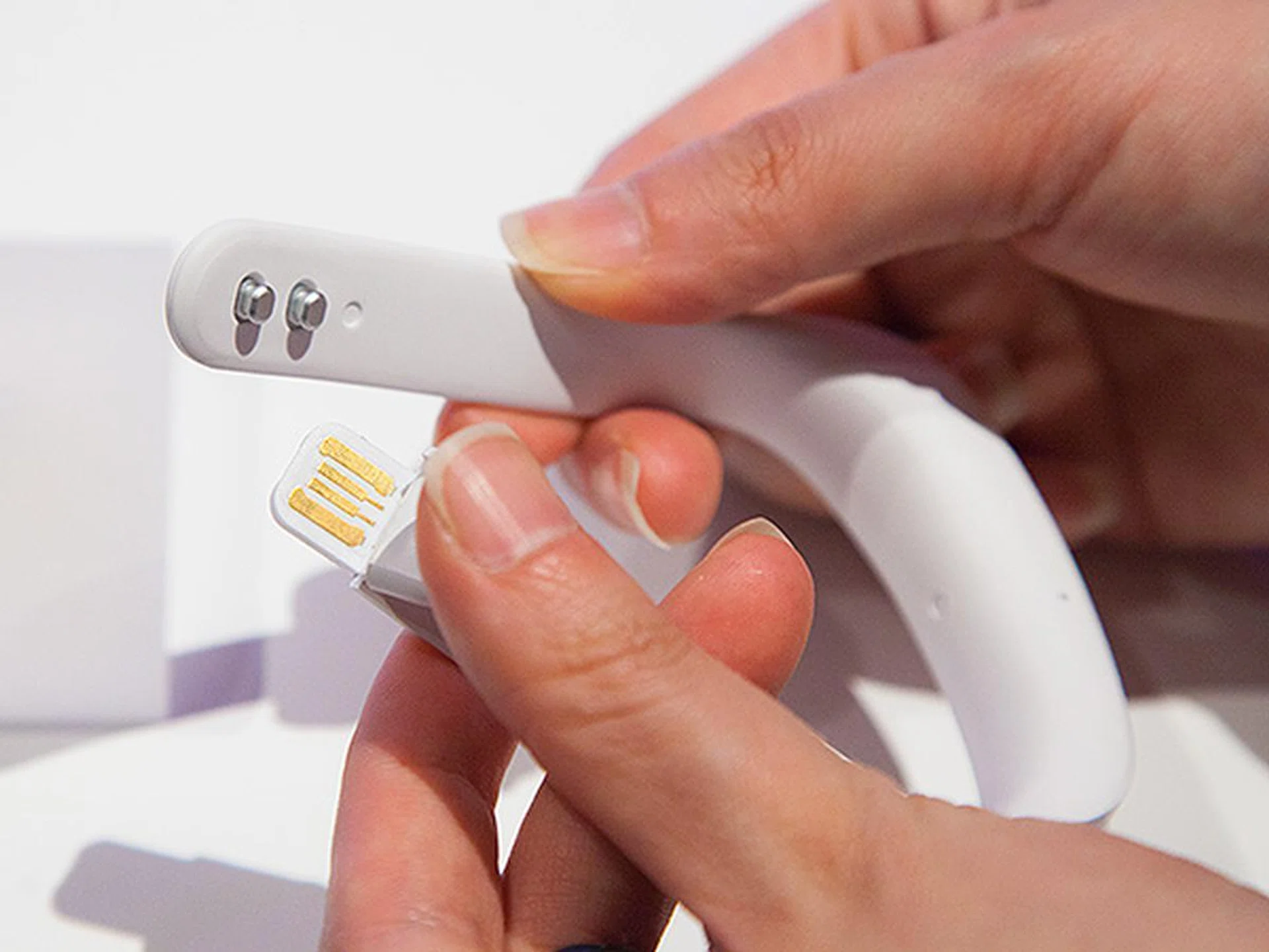 The USB connector is hidden and protected by a flexible flap at the end of the strap. The band can be worn and removed easily using the two metal hooks built into the strap as shown.