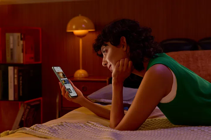 Model browsing content on the Redmi 15 5G in a suboptimally-lit bedroom while lying prone.