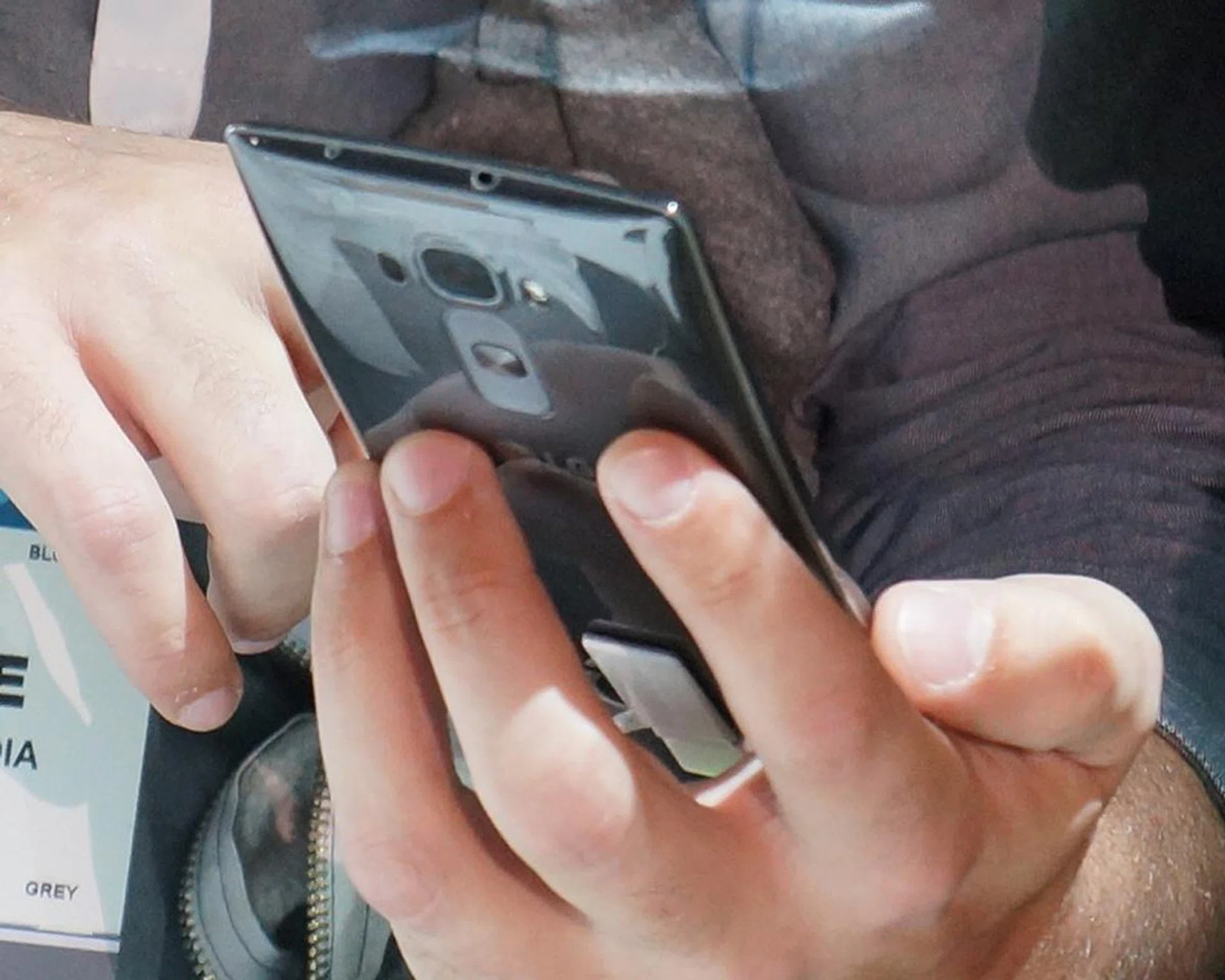 Here's the phone again from its back view while being handled/cradled by a user.