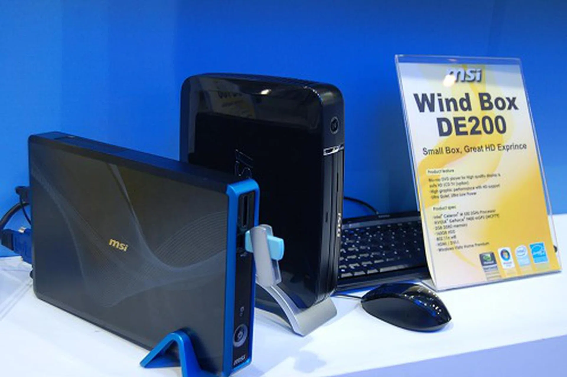  On the right, we've an interesting little DE200 nettop box. Using an Intel Celeron M 550 2GHz processor, it's able to deliver high performance Blu-ray playback support thanks to its choice of a NVIDIA GeForce 9400 mGPU. Also has a 160GB HDD, 2GB RAM, 802.11n WiFi and is loaded with Windows Vista Home Premium.  