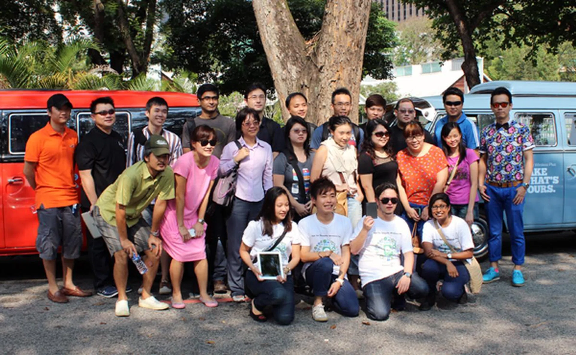 Participants posing for a photo in front of the brightly-colored Kombi vans before setting off to the event location.