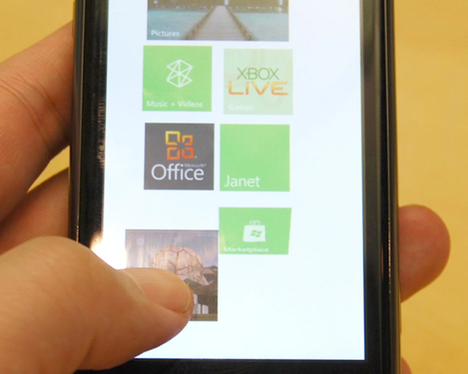 Adding specific multimedia files onto the screen as a live tile is possible on Windows Phone 7.