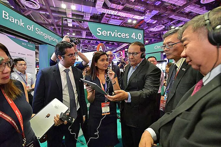 Ms. Apoorva Rai, executive director in the chief operating officer's office of the Bank of Singapore, explaining the bank's digital onboarding - the signing up for banking services entirely online - for private banking clients to Minister for Communications and Information S. Iswaran yesterday at Innovfest Unbound, the anchor event of the Smart Nation Innovations Week. Photo: Ng Sor Luan