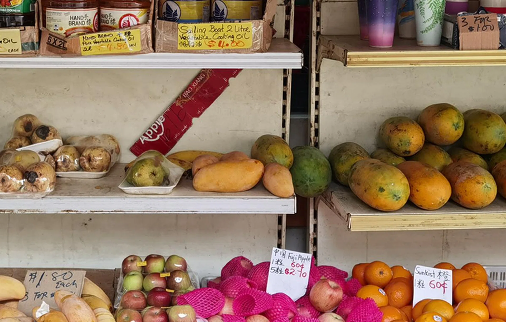 100% crop of the above image. Every little detail is clear, from the brand of cooking oil, to the blemishes on the fruits, their prices, and the clear plastic packaging used.