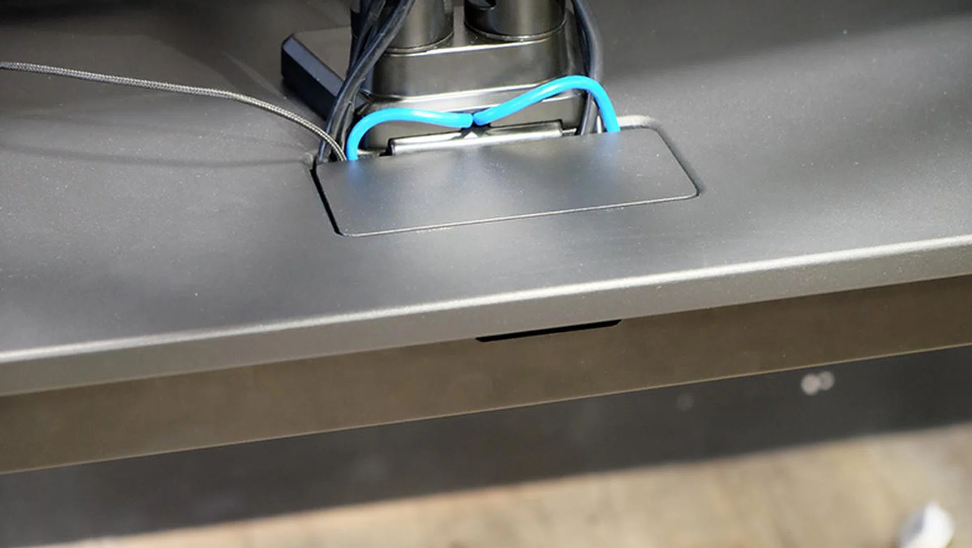 The compartment at the base of the monitor stand leads to the cable management tray.