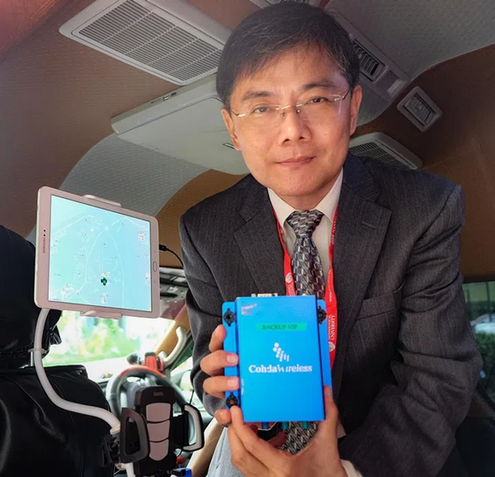 NTU Assoc Prof Guan Yong Liang holding a smart on-board unit with a display of the NTU-NXP smart mobility test bed. (Image source: NTU, Singapore)