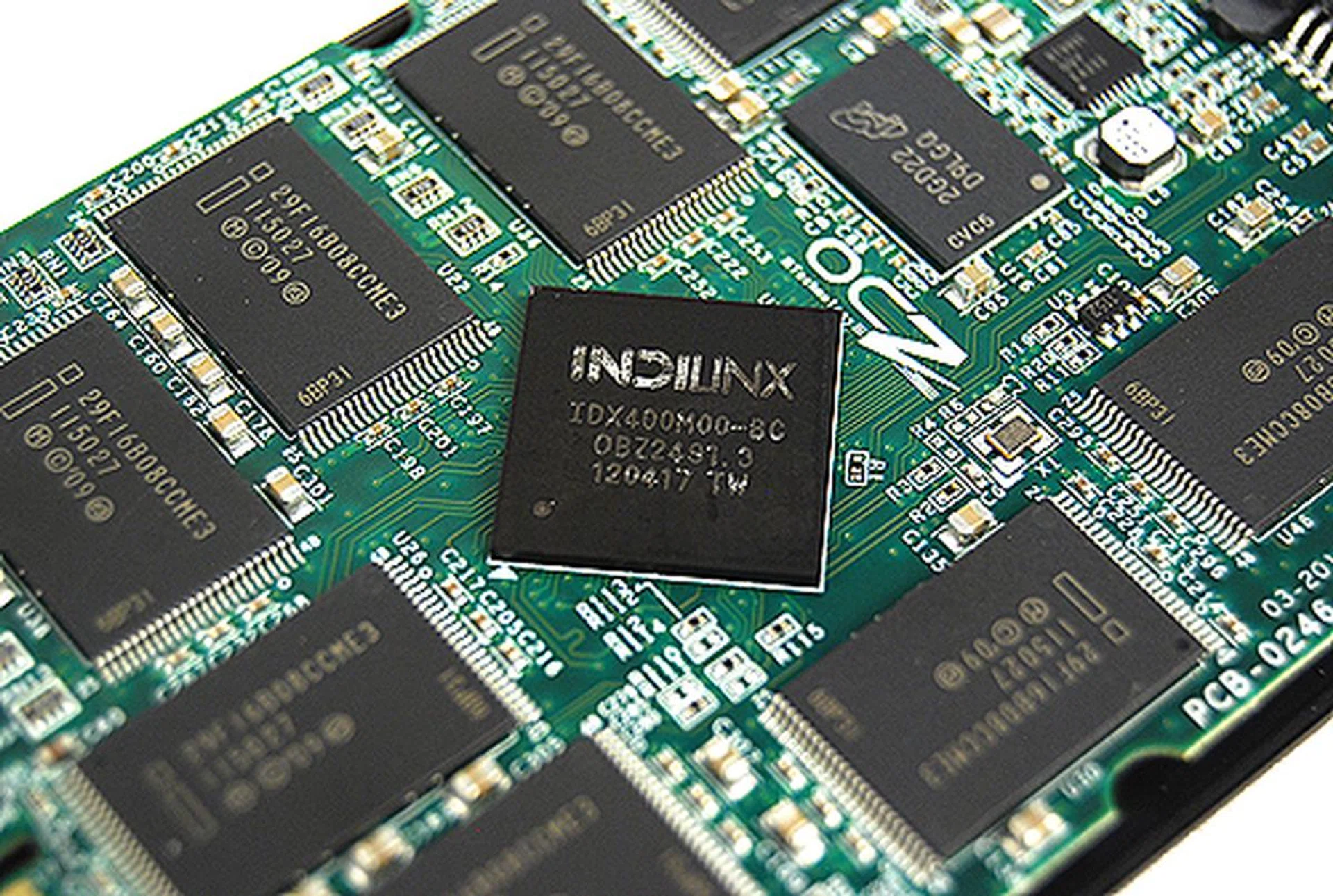 A closer look at Indilinx Everest 2 controller. It is surrounded by Intel 25nm NAND chips of 16GB density. The smaller chip to the top right of it is a single 512MB cache chip. There's another cache chip on the opposite side along with another eight NAND chips.