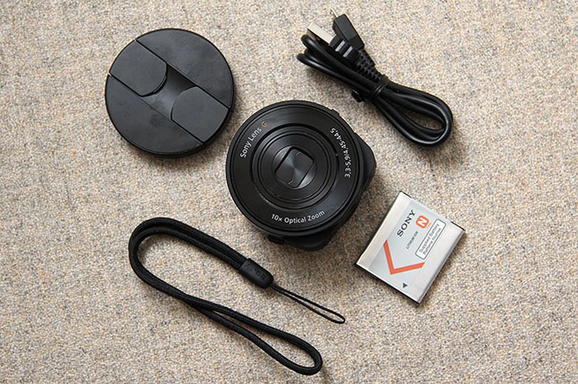 The Cyber-shot DSC-QX10 comes with a smartphone attachment which lets you mount the camera onto your phone. Other items in the box include the battery, USB cable, and wrist loop.