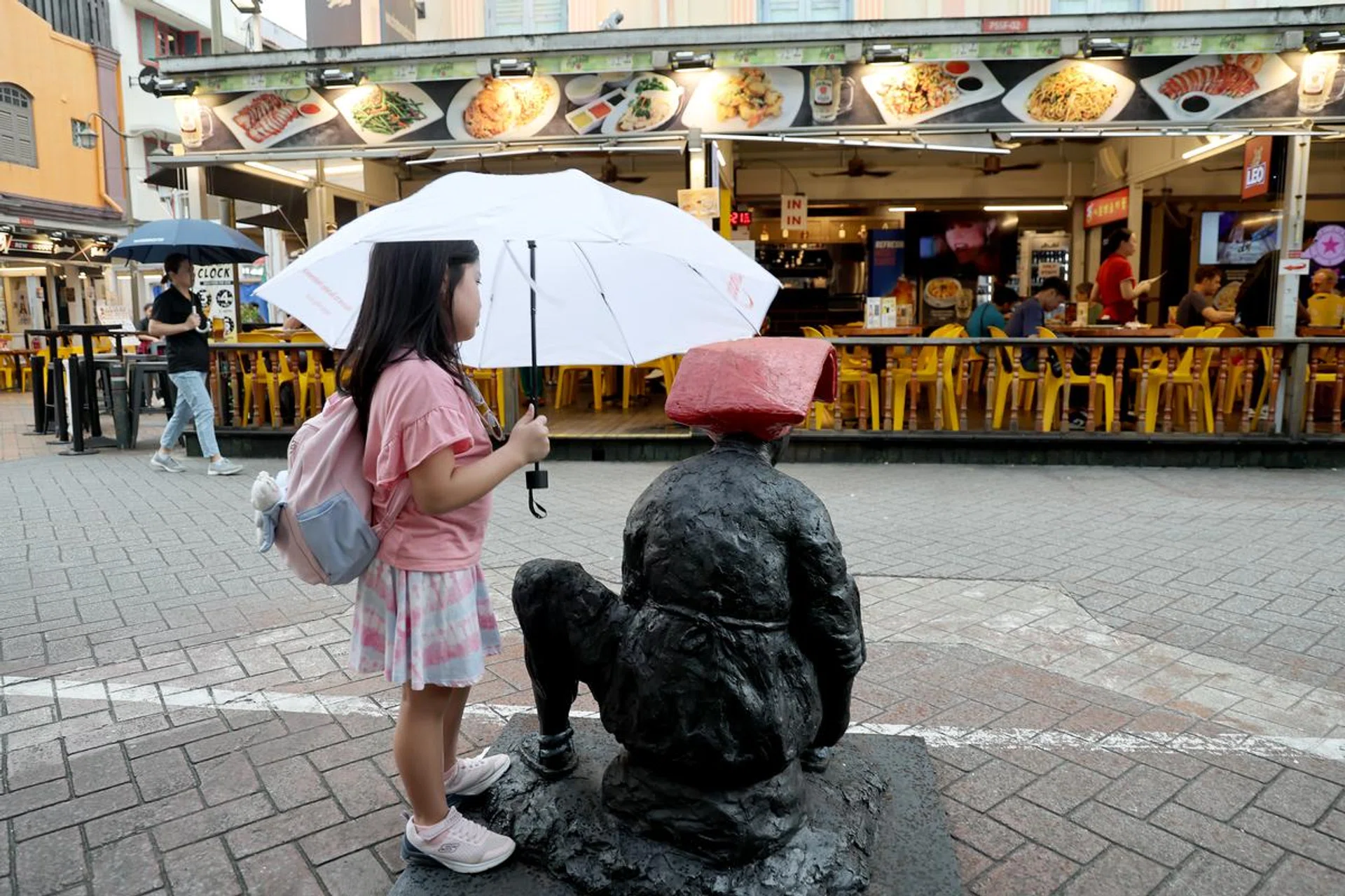 This young girl is offering an umbrella to the hardworking “samsui woman”. Shooting info: 24mm at f/4, 1/60s, ISO 125. Photo: HWZ (Click to see image in full resolution)