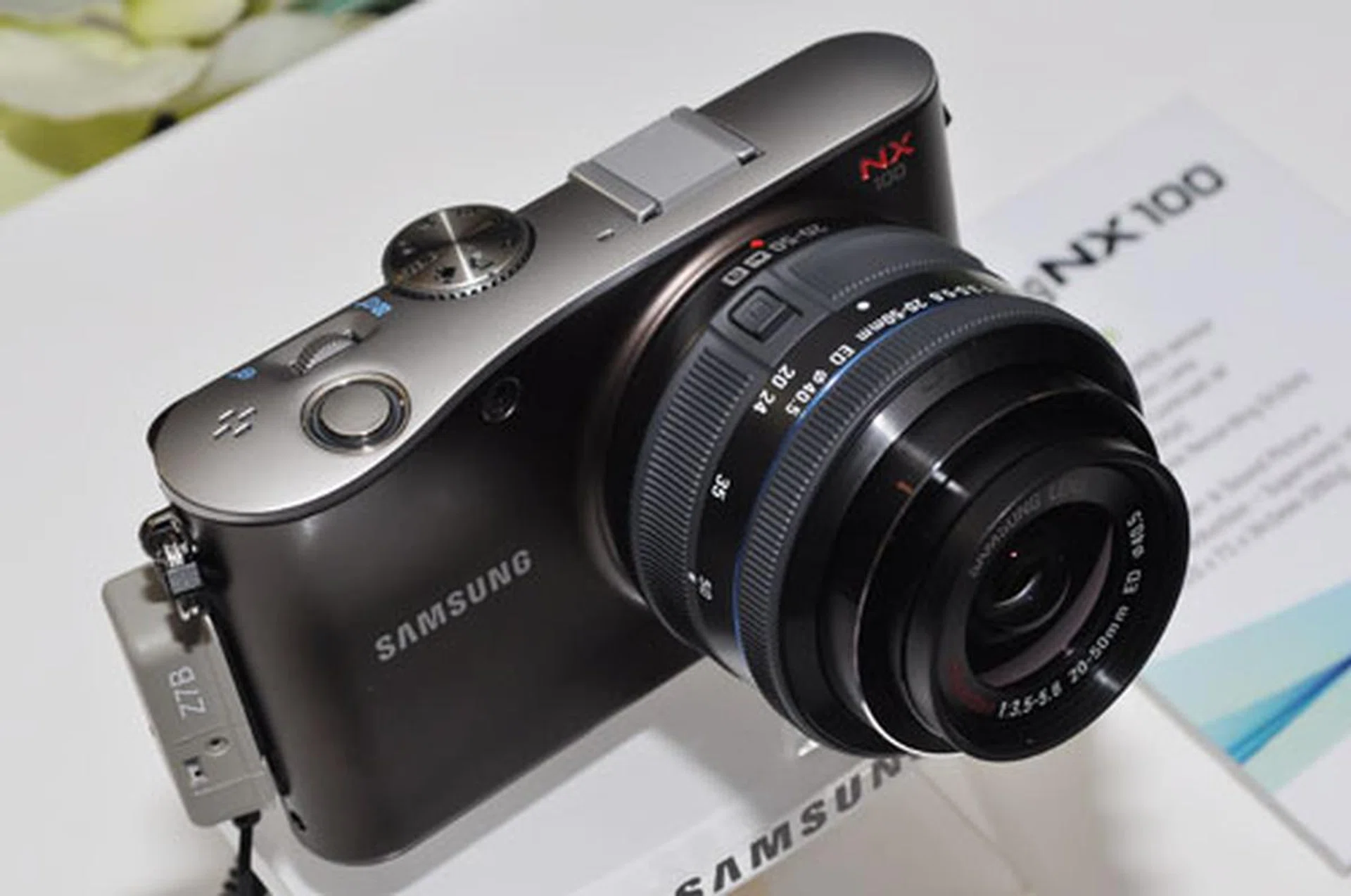 Samsung says the design of the NX100 is inspired by the simple shape of dew forming on a leaf, reflected on the shutter button and curved body.
