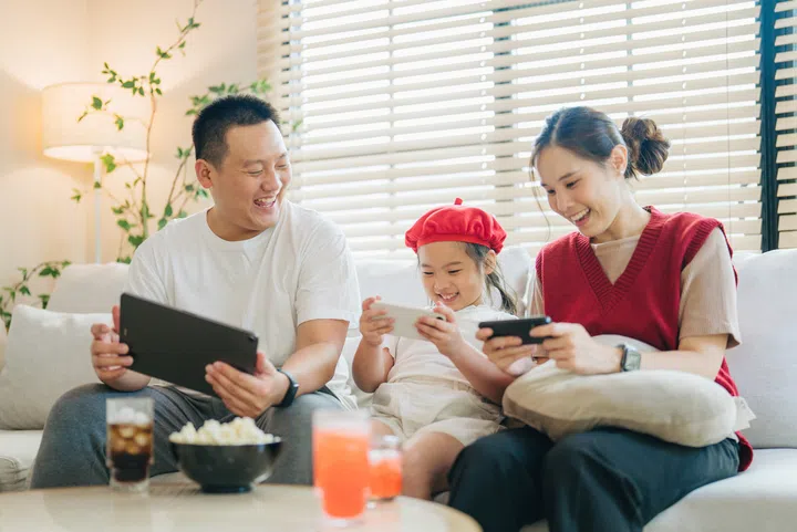 Portrait of Happy asian family smiling while sitting on sofa in living room on weekend, all looking at camera.