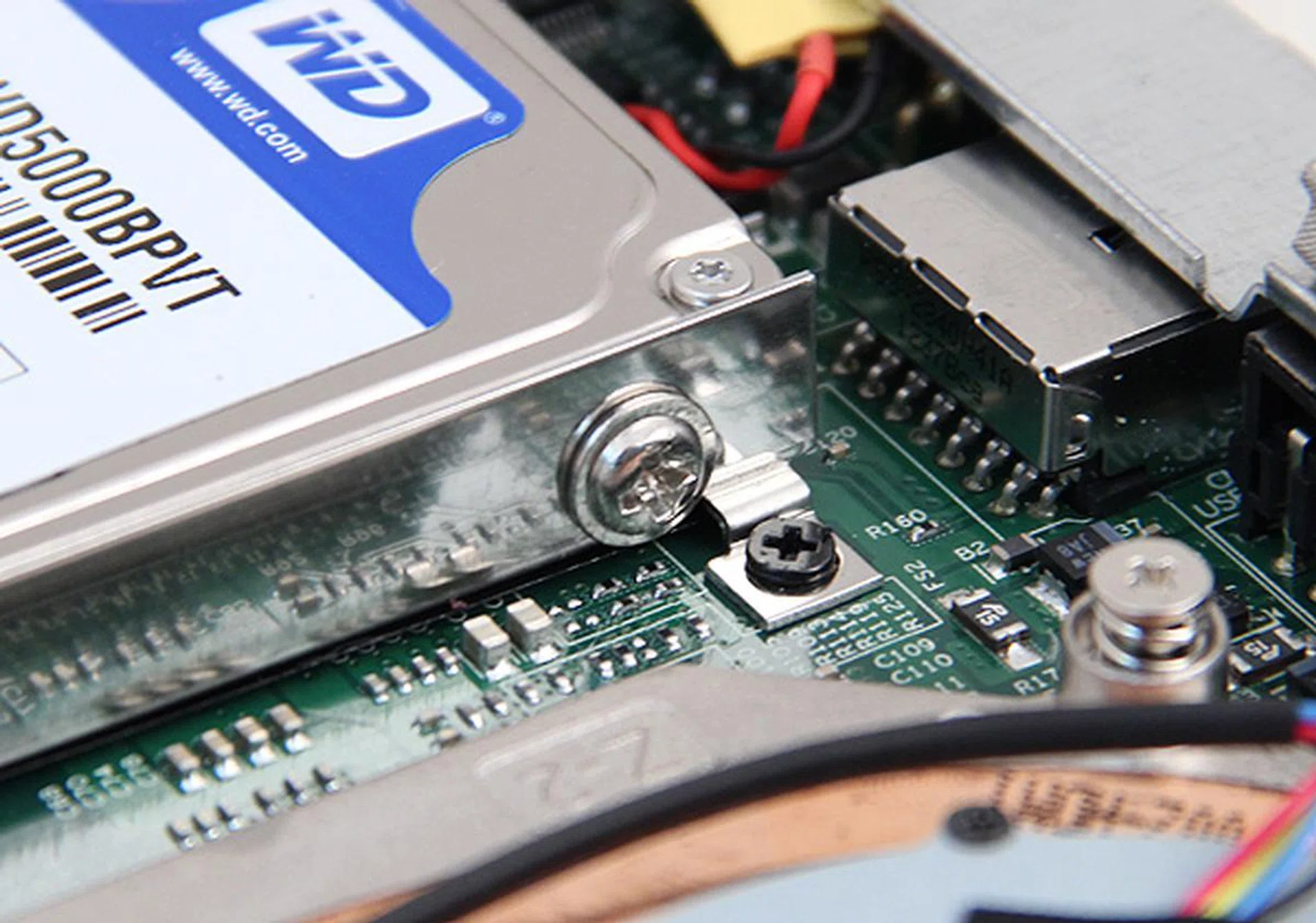 Removing the hard disk proved to be quite troublesome since you cannot just unscrew the drive from the cage (silver screw), you need to remove the entire hard disk cage (black screw).