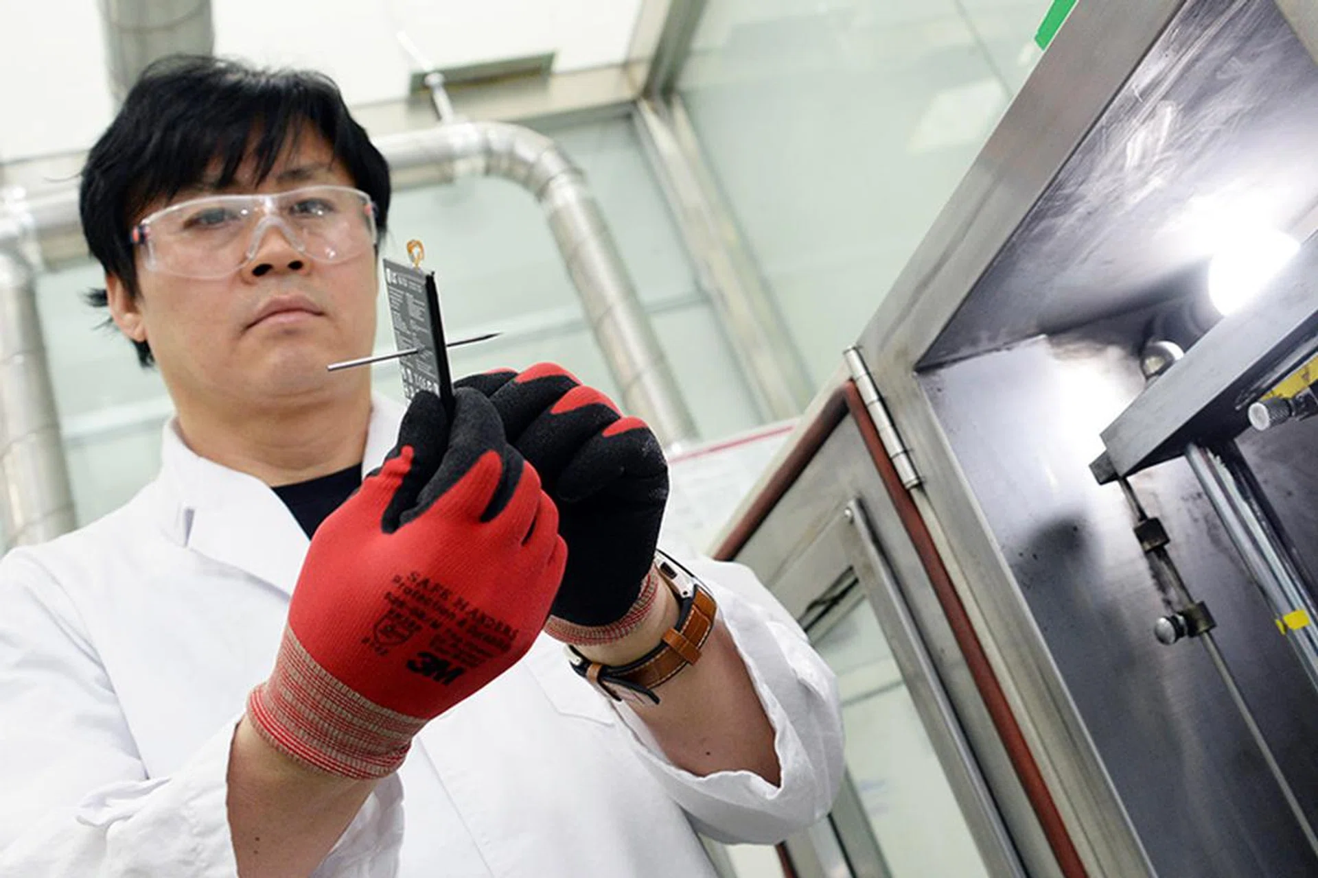 An LG technician holds up a battery that has been punctured by a nail. Image source: LG.
