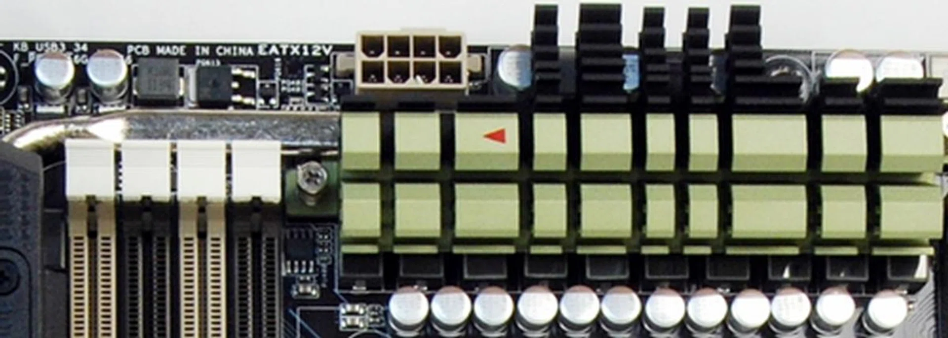 The silver heatpipe extends from the olive green heatsink into the TUF Thermal Armor I/O port plastic sheath. Notice the tiny red arrow indicating the direction of the heat flow.