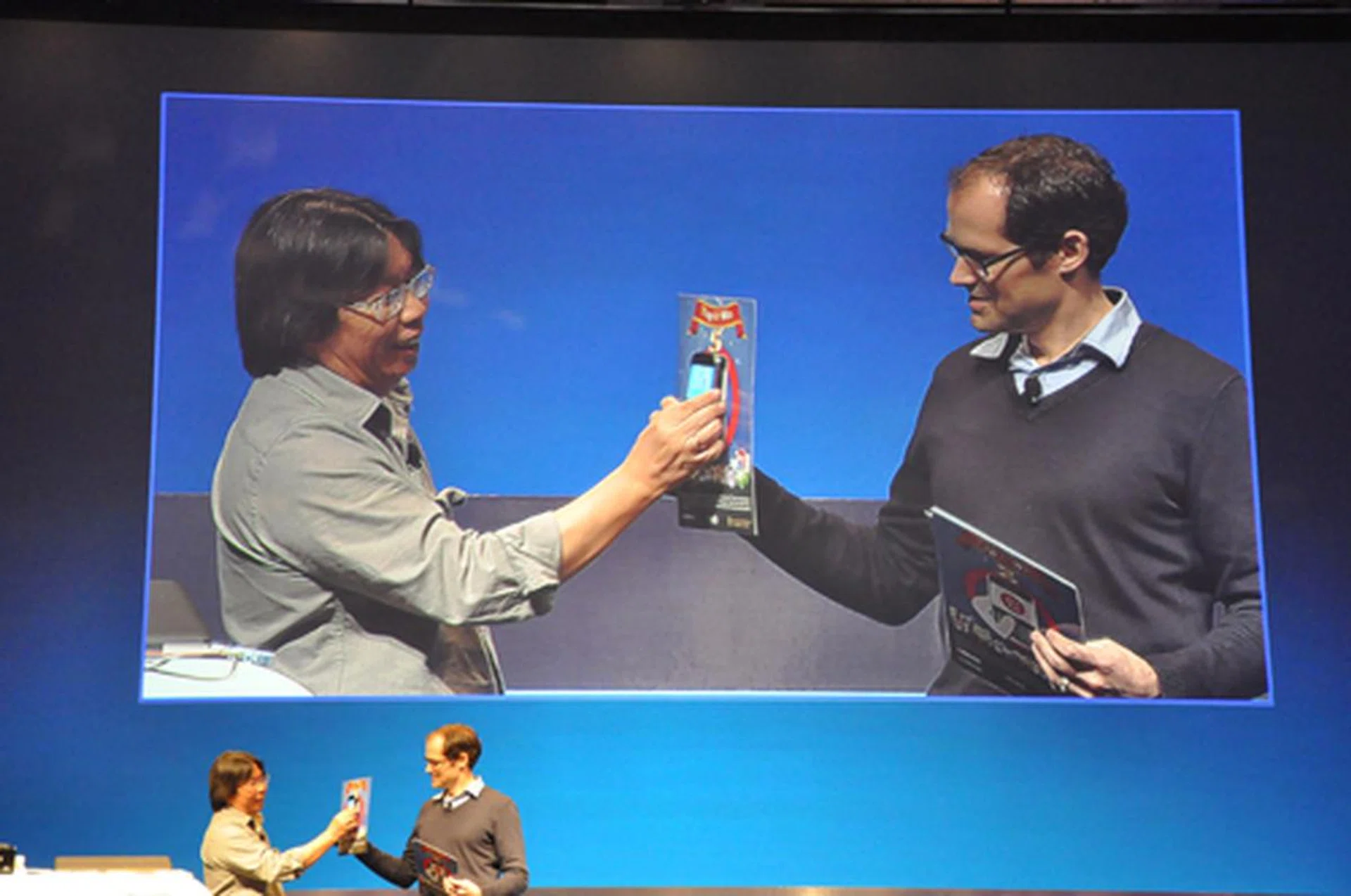 Christopher Smith, Vice President, Handheld Applications Platform & Tools gets a live demonstration of a game called Treasure Hunt that relies on NFC technology. Shown above, a player simply users his or her mobile phone to tap on cards to collect points.