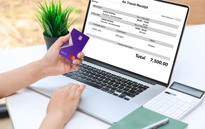 Stock image of using YouTrip to pay for flight tickets, logging it with other travel-related expenses.