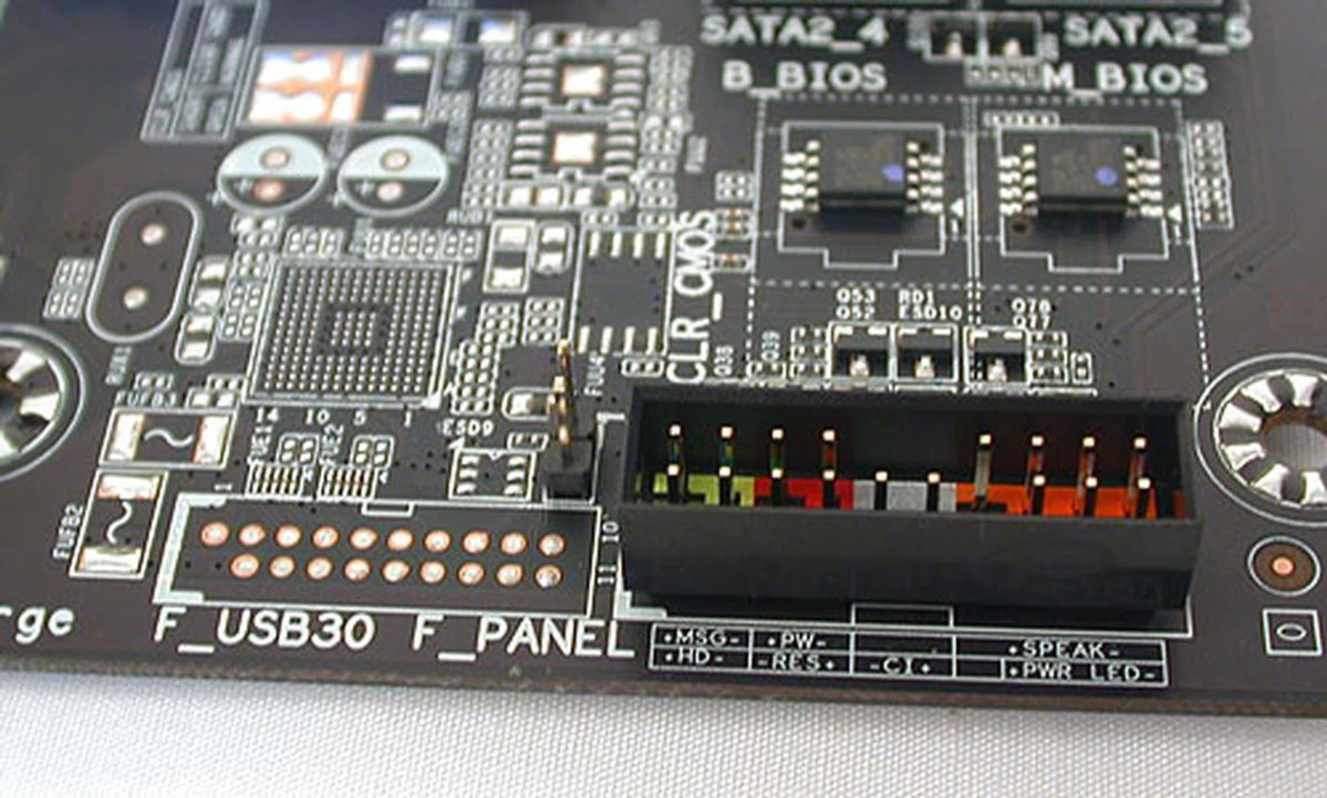 The front panel connectors and the clear CMOS pins which you need to short when you want to reset your BIOS to its default state. Notice the empty solder points and silk-screening which dictate the same board layout is shared with its higher-end counterparts.
