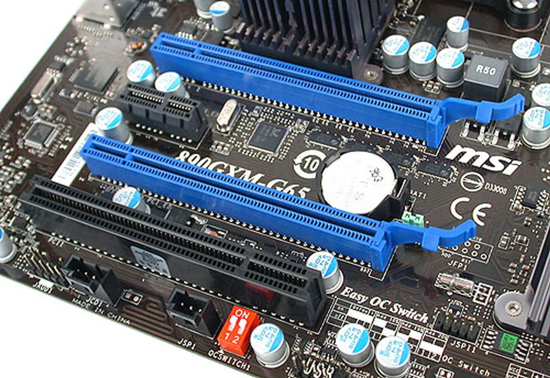 You can still do CrossFireX on this mATX board, but dual slot cards will completely fill up your slots, including the neighbouring PCIe x1 and PCI slots. At the bottom of this image, you can see the small red OC Switch that allows for FSB overclocking via that switch. It's all a bit old-school and something that we had though MSI had given up for its newer OC Genie implementation.