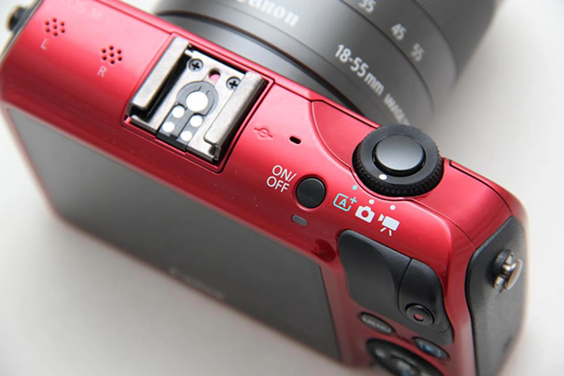What looks like a zoom toggle is the EOS M's limited Mode dial, which lets you select from Scene Intelligent Auto, Creative Auto (plus other modes via the on-screen menu) and Video.