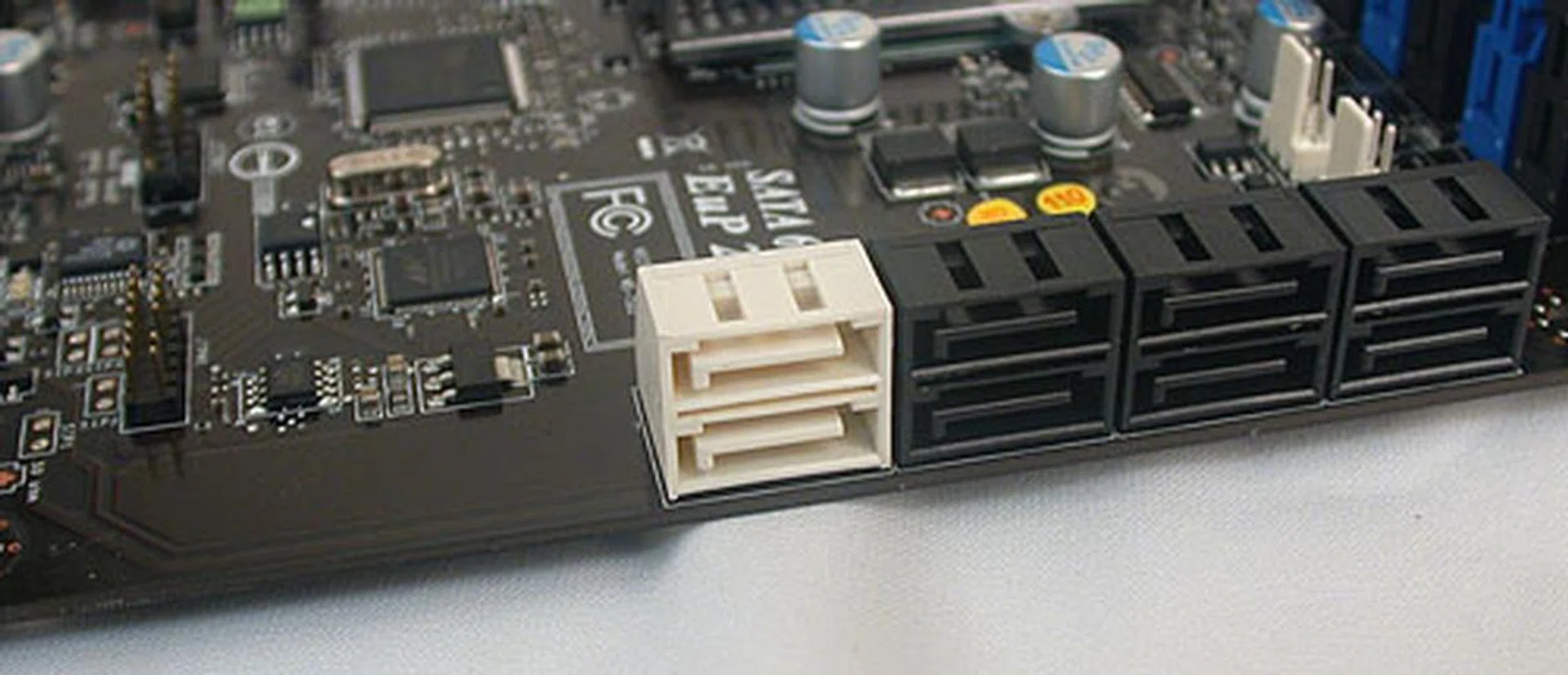 The two white ports are SATA 6Gbps versions, with six other black SATA 3.0Gbps ones. The amount of extra PCB besides the white SATA ports hint at this design being reused from a higher-end X58 board. Or it could just be the IDE connector that has been removed. 