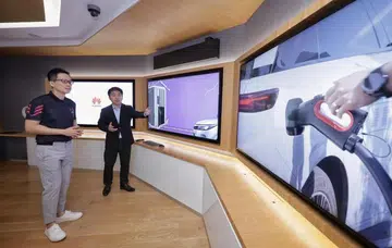 EV-electric CEO Derek Tan (left) and Huawei Digital Power Singapore managing director Terry Gao watching a video presentation on an ultra-fast charging station at Huawei's Singapore AI lab. (Image source: The Straits Times).