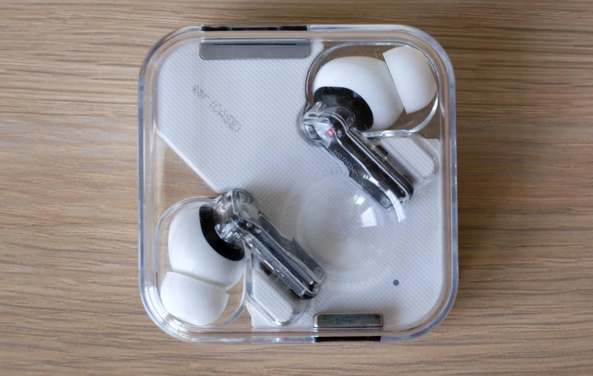 The charging case is transparent and charges wirelessly or through USB-C.